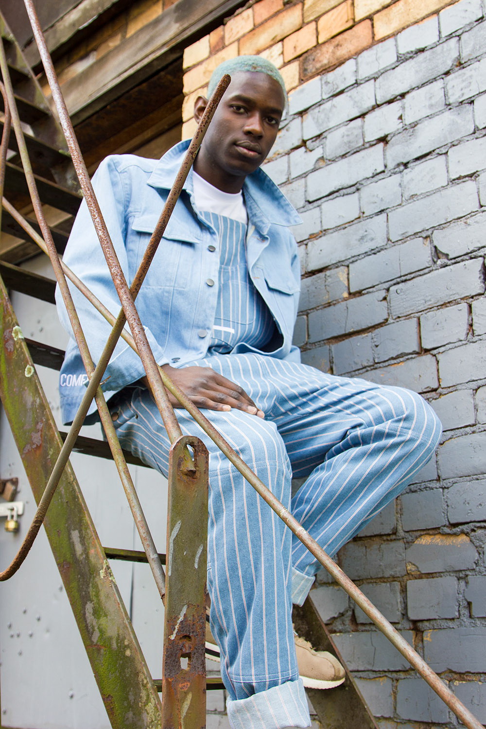 out of comfort menswear worn by masculine-presenting model sitting on steps