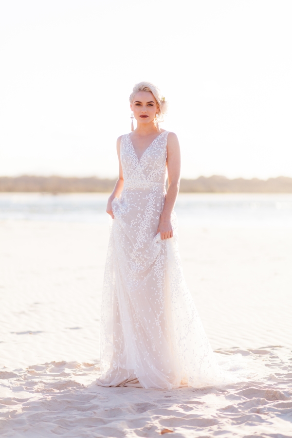 erin clare bridal. model wears beautiful white wedding gowns on a beach