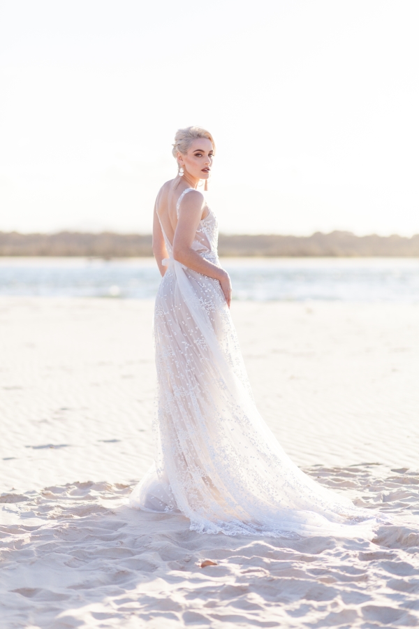 erin clare bridal. model wears beautiful white wedding gowns on a beach