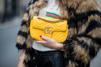 gucci bag held by woman in gucci shirt with fur coat