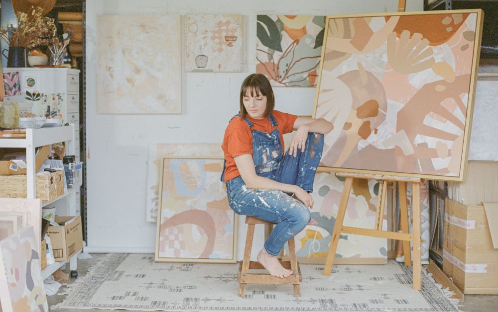 artist sitting beside canvas