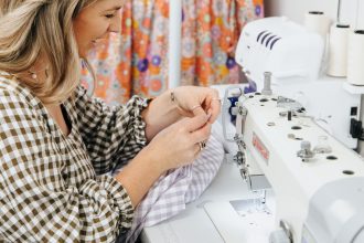 woman designer Danni Rose sitting at sewing machine with gingham fabric