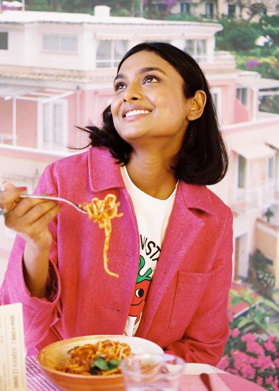 woman in magenta blazer eating spaghetti