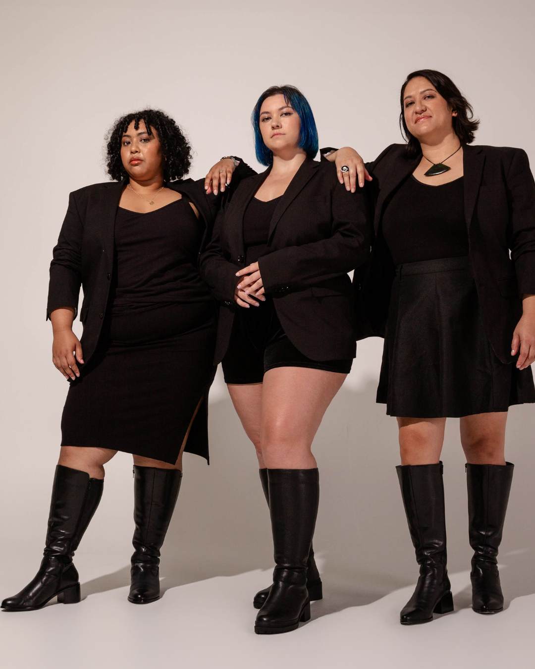 Three women standing modelling black knee high boots. Luxury Brand Expands Size Range.